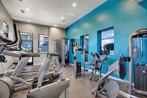 A gym with a blue wall and a treadmill at The Henley Apartments, California