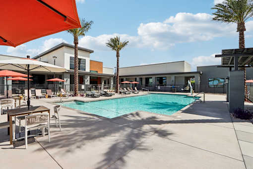 A pool area with a red umbrella and a palm tree at Ironwood Ranch Apartments,Maricopa,AZ