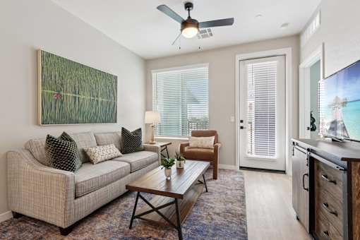 A living room with a couch, a coffee table, and a painting on the wall at Ironwood Ranch Apartments,Maricopa,Arizona