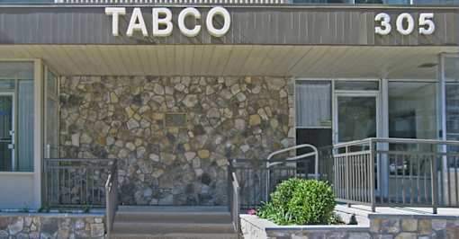 The front of a building with a stone wall and a sign at Tabco Towers Apartments, Towson, 21286