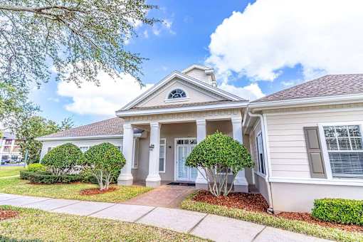 A house with a front porch and a tree in front at The Villages on Millenia Apartments, Orlando 32839