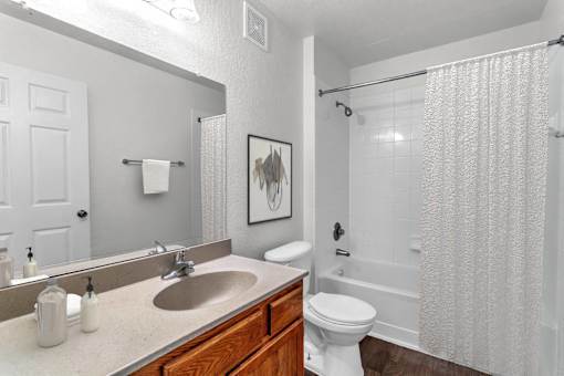 A bathroom with a white toilet, sink, and shower curtain at The Villages on Millenia Apartments, Florida, 32839