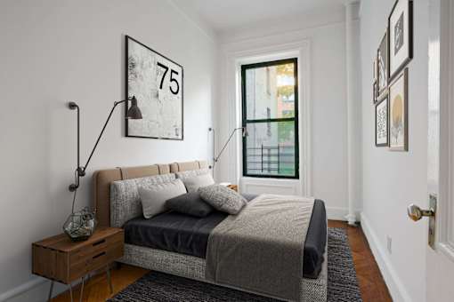 A bedroom with a bed, nightstand, and a picture frame on the wall.