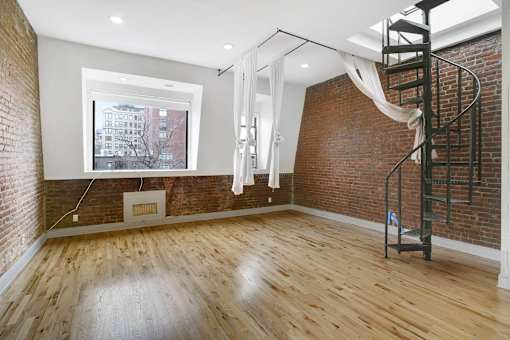 A room with a spiral staircase and a window overlooking a cityscape.