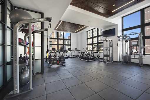 A gym with a variety of equipment including a squat rack, a bench press, and a rowing machine.