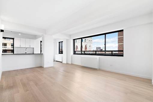 A spacious room with wooden flooring and large windows.