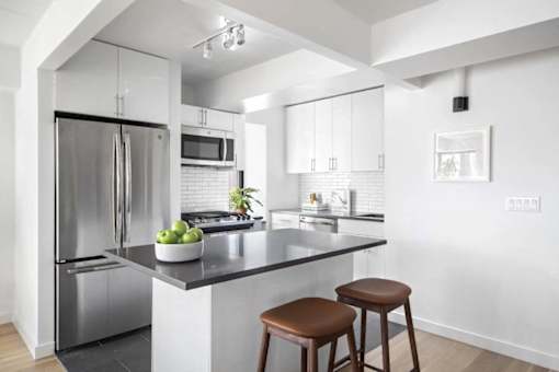A modern kitchen with a stainless steel refrigerator and a black countertop.