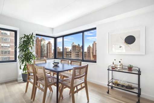 A dining room with a table and chairs and a view of the city.