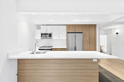 A modern kitchen with a white countertop and wooden cabinets.