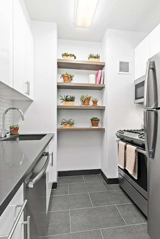 A kitchen with a stainless steel refrigerator and a countertop with a sink.