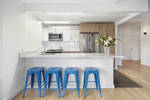 A kitchen with a white counter and blue stools.