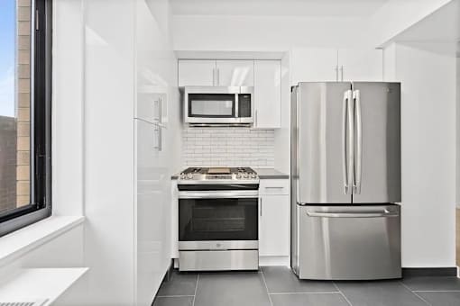 A modern kitchen with a stainless steel refrigerator and oven.
