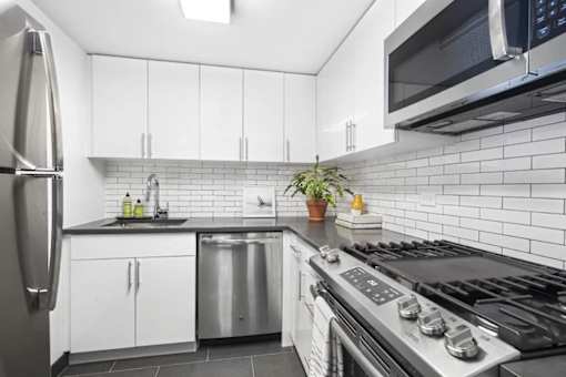 A modern kitchen with a stainless steel refrigerator, microwave, and stove.
