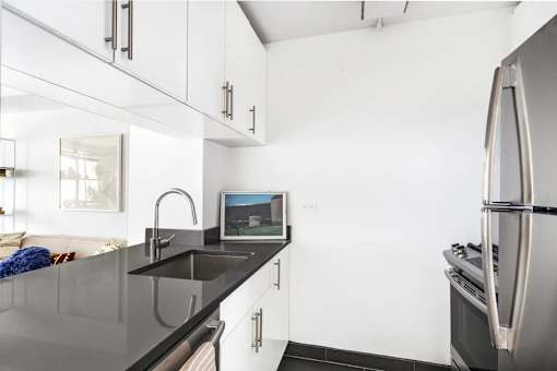 A modern kitchen with a black countertop and stainless steel appliances.