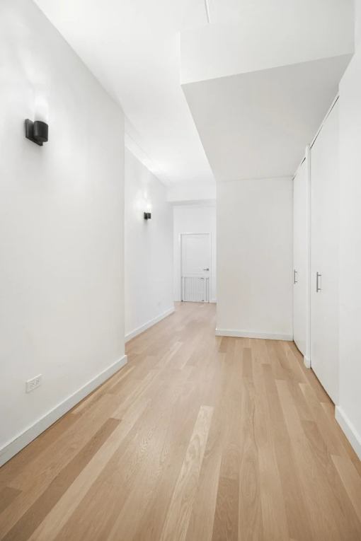 A long hallway with wood floors and white walls.