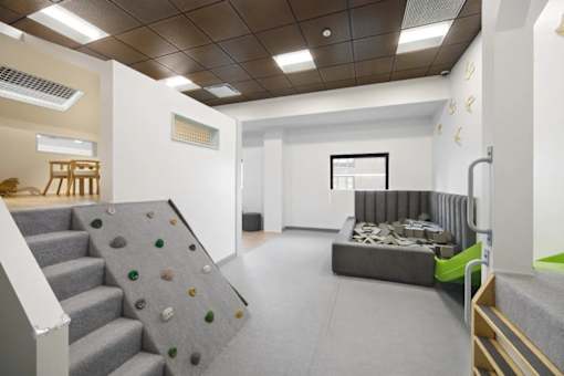 A room with a grey carpet and a grey wall with a window.
