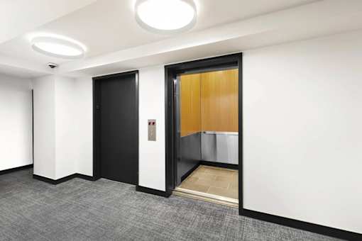 A hallway with a black door and a wooden door.