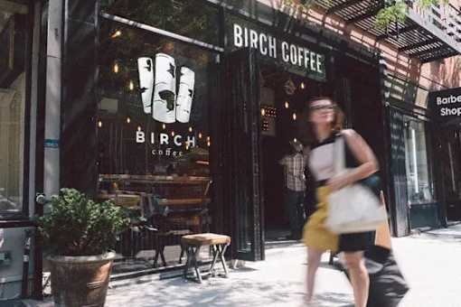 A woman in a yellow dress is walking past a coffee shop.