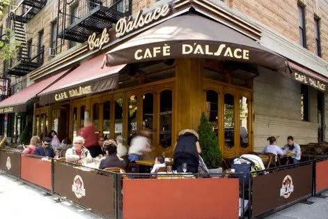 A group of people are sitting at tables outside of a cafe named DALSACE.