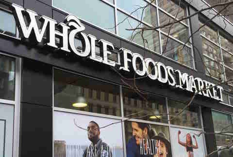 A Whole Foods Market storefront with a man standing in front.