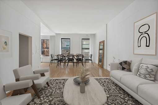 A living room with a white couch, a coffee table, and a painting on the wall.
