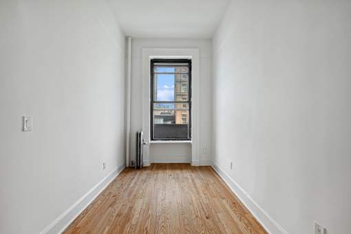 A room with a window and wooden floors.