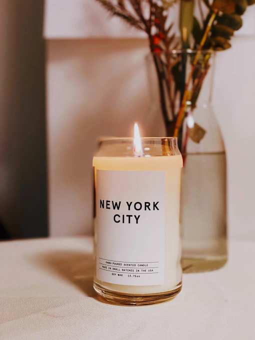 A New York City scented candle is lit and placed on a table.