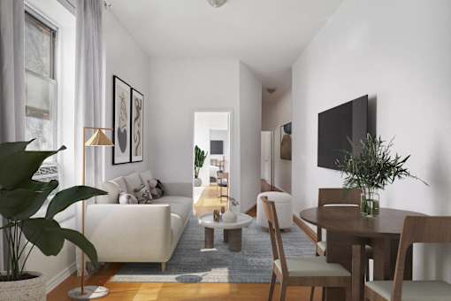 A living room with a white couch, a wooden table, and a television on the wall.