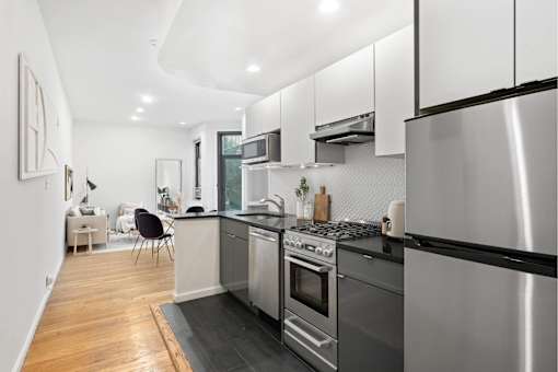 A modern kitchen with stainless steel appliances and wooden flooring.