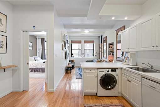 A modern kitchen with white cabinets and a washing machine in the middle.