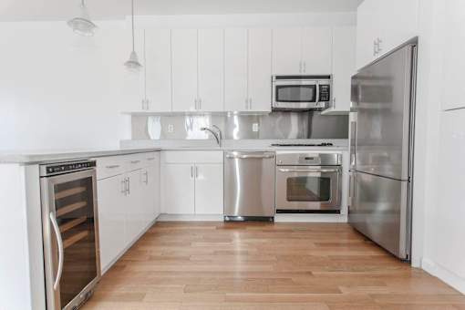 A kitchen with stainless steel appliances and wooden floors.