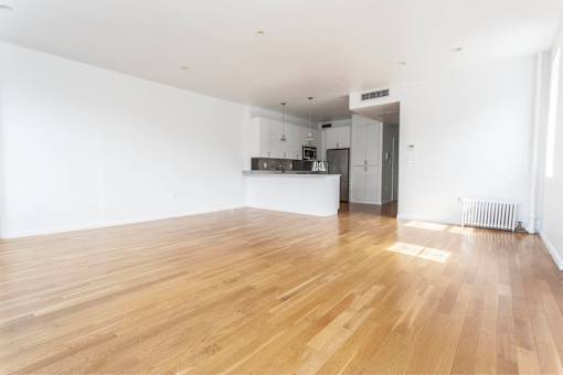 A spacious room with wooden flooring and white walls.