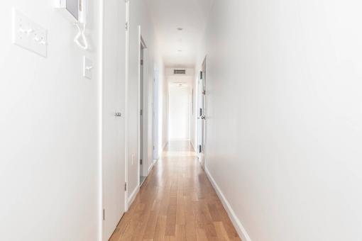 A long hallway with white walls and wood floors.