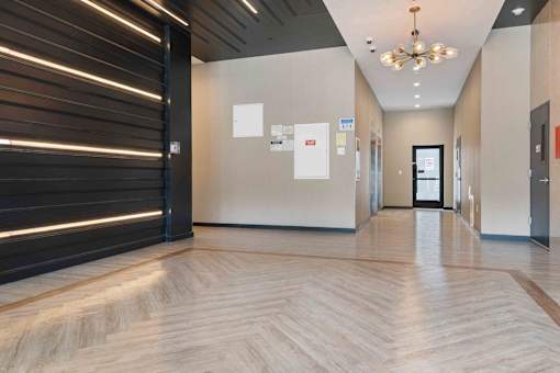A hallway with a wooden floor and a black door on the left.
