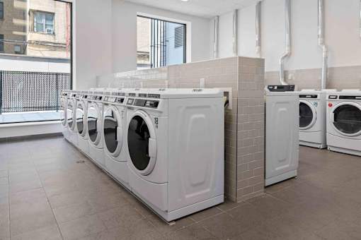 A row of white front load washing machines in a laundromat.