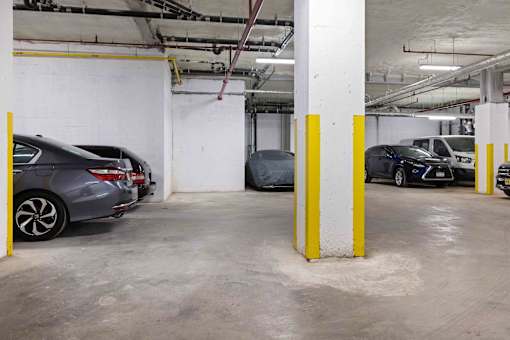 A parking garage with cars parked and yellow poles.