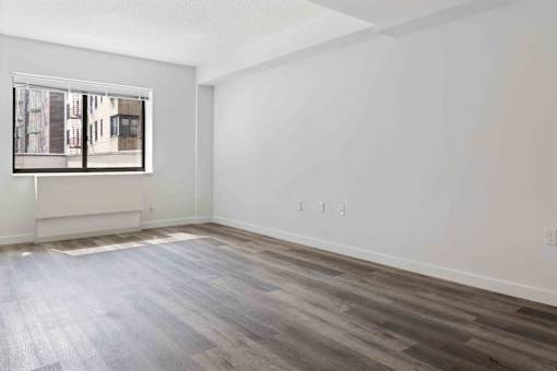 A room with a window and wooden flooring.