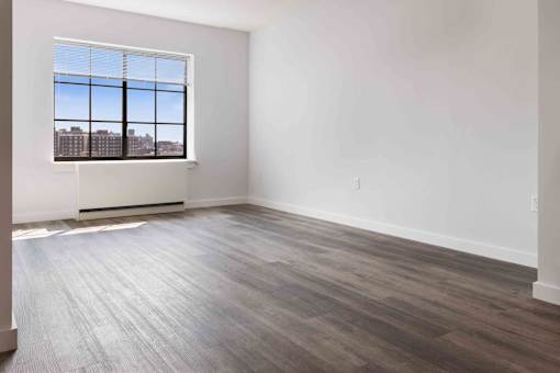 A room with a large window and wooden flooring.