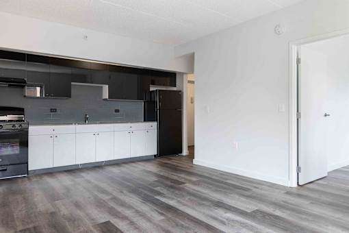 A modern kitchen with dark wood floors and white cabinets.