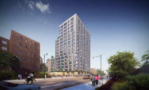 A tall building with many windows is in the middle of a street with people walking on the sidewalk.