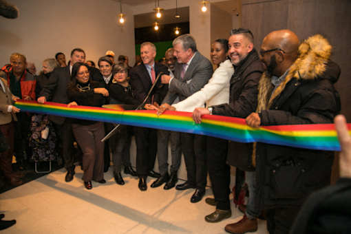 A group of people are gathered around a ribbon at a ribbon-cutting ceremony.