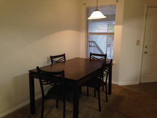 A brown wooden dining table with four chairs.