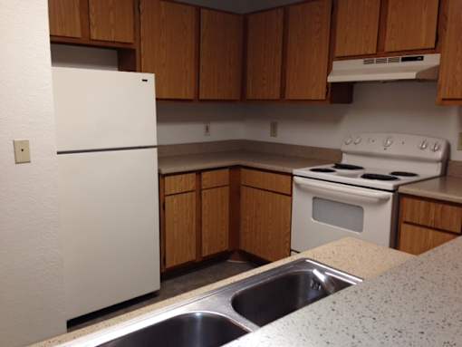 A white refrigerator is in a kitchen with wooden cabinets.