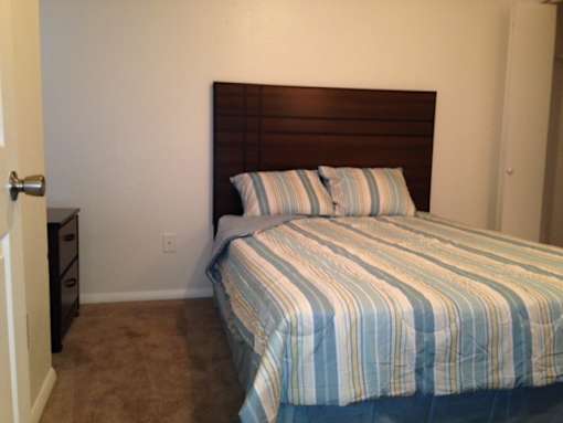 A bed with a blue and white striped comforter sits in a room with a brown headboard.