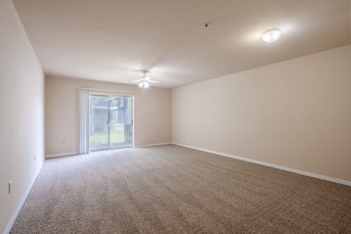 an empty living room with carpet and a sliding glass door