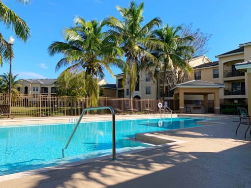 Portofino Apartments resort style pool and lounge chairs with palm tree in lush greenery at Portofino, Florida