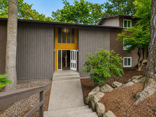 A modern house with a wooden door and a stone pathway leading to it.