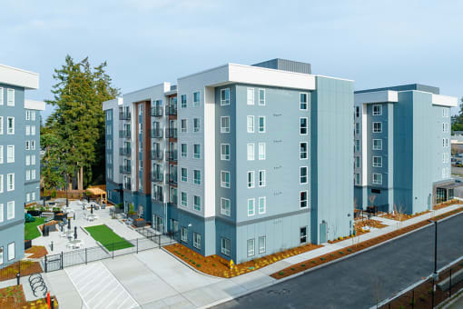 a rendering of a blue and gray apartment building with a sidewalk in front of it