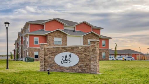 Monument Sign with Landscaping and Building Exterior View at Salish Flats APARTMENTS, Airway Heights, WA