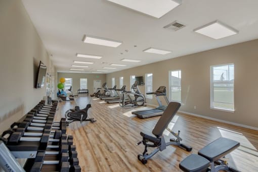 New Apartments in Airway Heights-Salish Flats-Fitness Center with Equipment, Hardwood Style Flooring, a TV, and Large Windows at Salish Flats APARTMENTS, Airway Heights, WA 99001